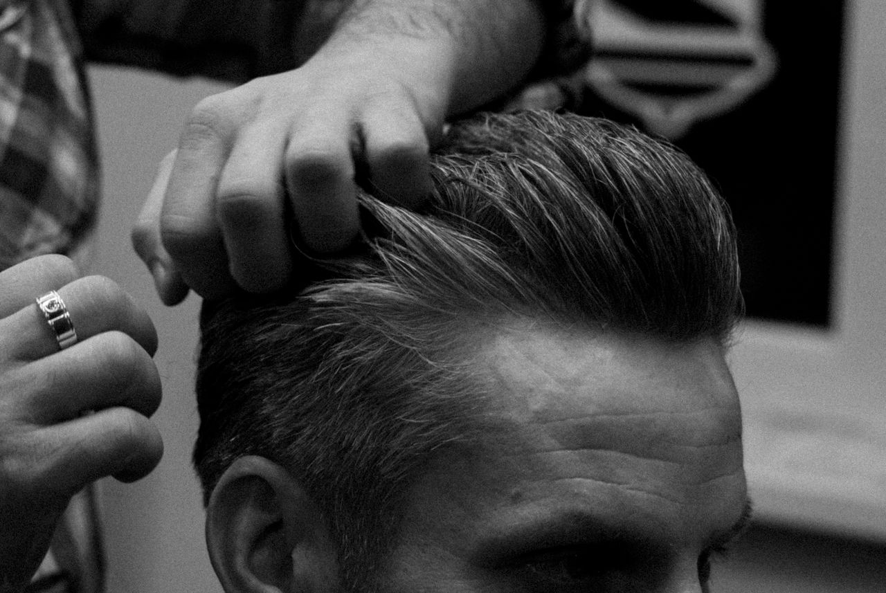 services-01 Barber styling a man's hair in a Moscow salon, captured in grayscale.
