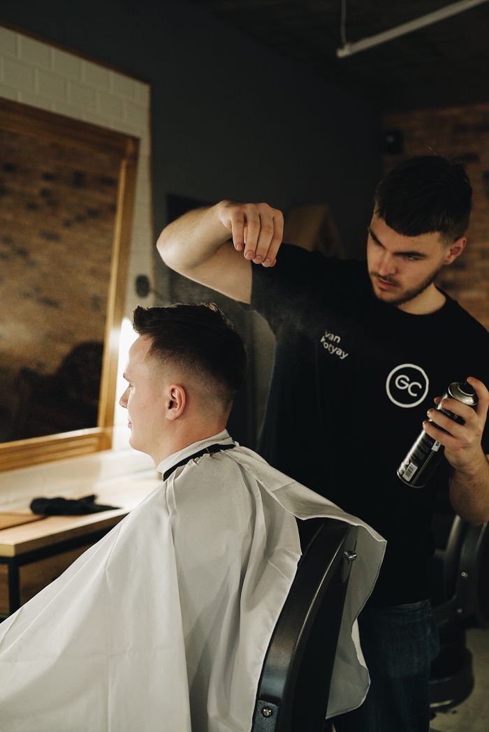 The Art of Drawing Readers In: Your attractive post title goes here Barber styling client's hair in a contemporary shop, showcasing grooming and care.