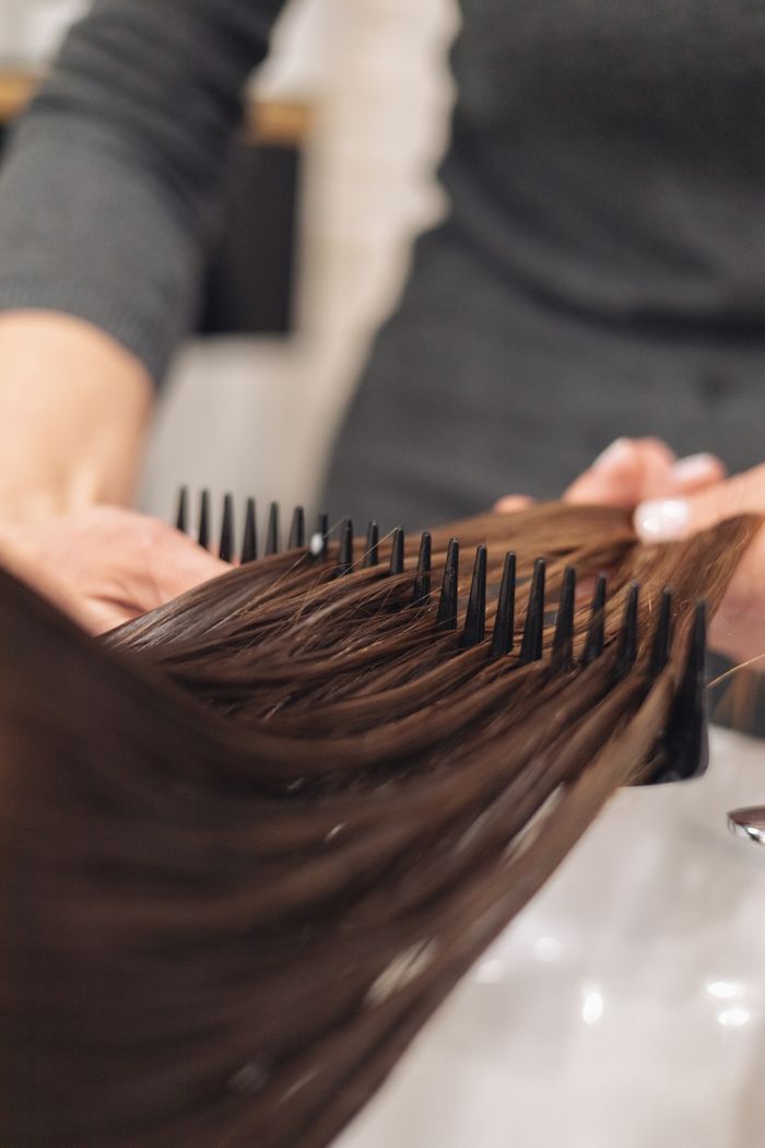 Crafting Captivating Headlines: Your awesome post title goes here A hairdresser skillfully combs wet hair, focusing on smooth styling in a salon setting.